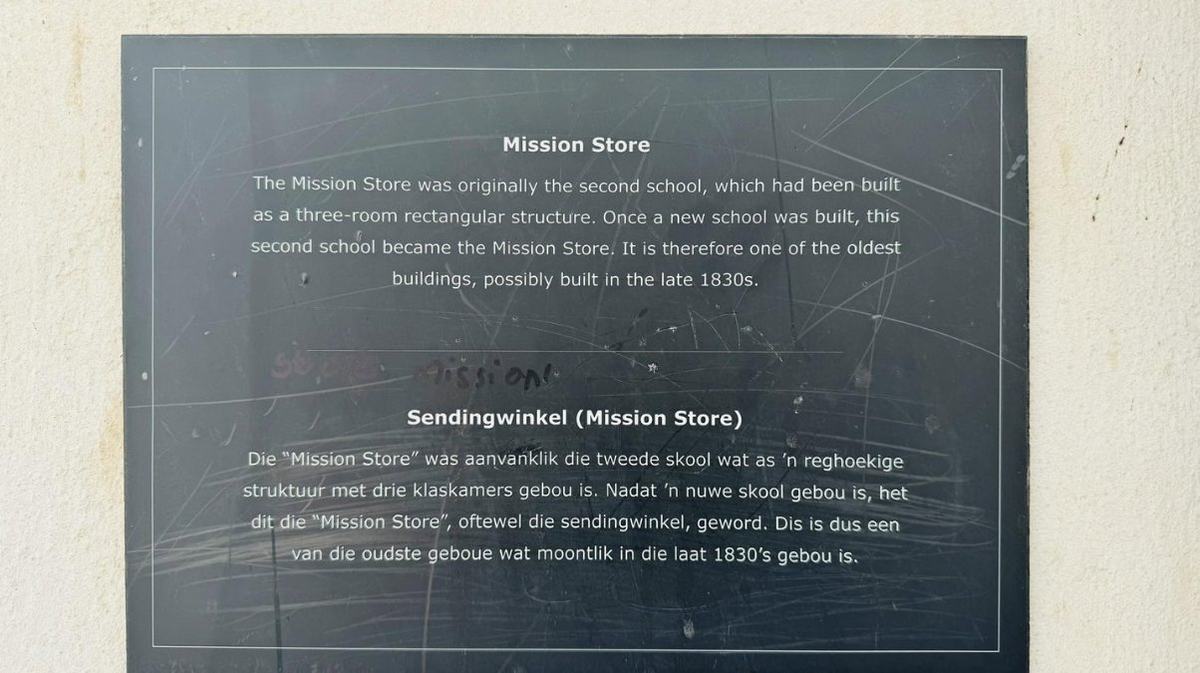 Heritage plaque on the Wupperthal Mission Store explaining, in English and Afrikaans, that it was originally the village's second school